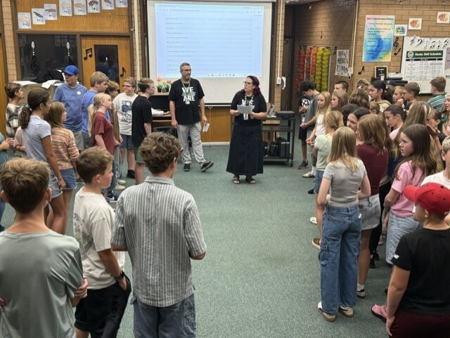Students and administrators participate in an icebreaker activity in the choir room.