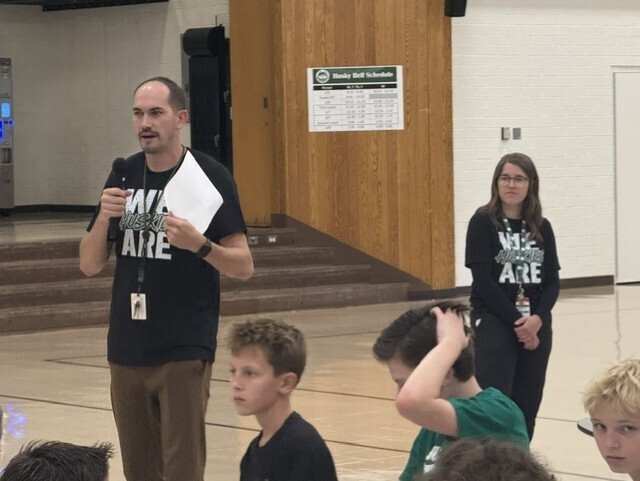 Counselors in 'We Are Huskies' shirts address students in the cafeteria.