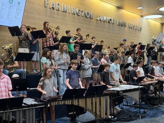 Farmington Junior High band students play trumpets, trombones, clarinets, and percussion instruments in the Commons.