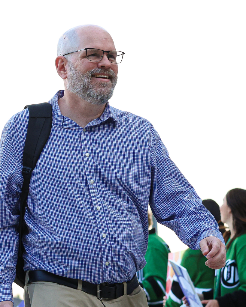 A teacher smiling as they walk into a school.