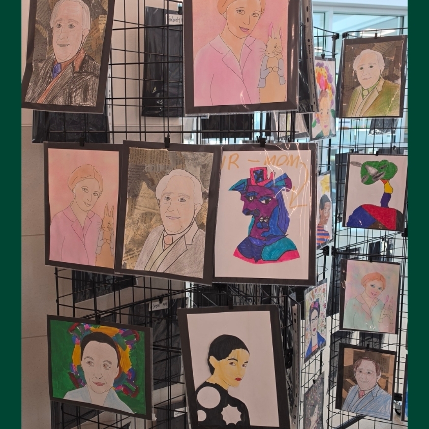 A hallway art display shows several student-created portrait projects clipped to black grid panels.