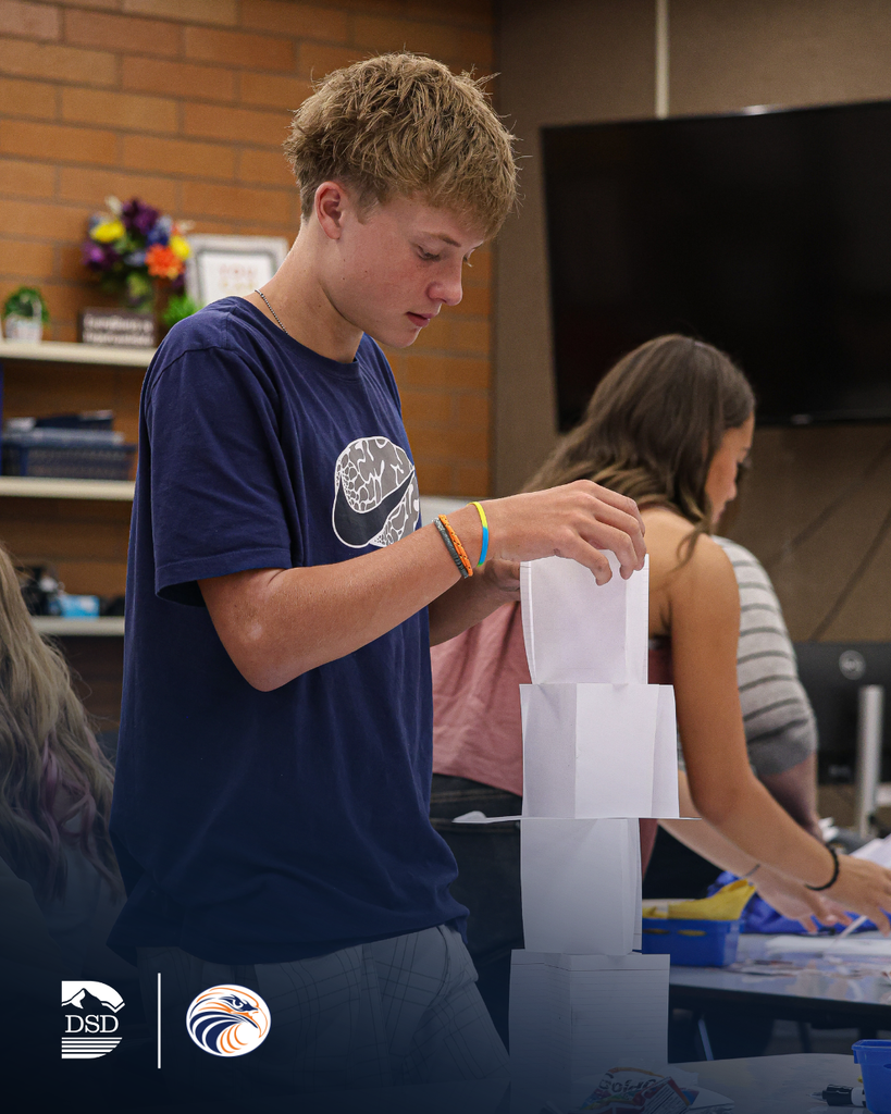A student building a paper tower in class.