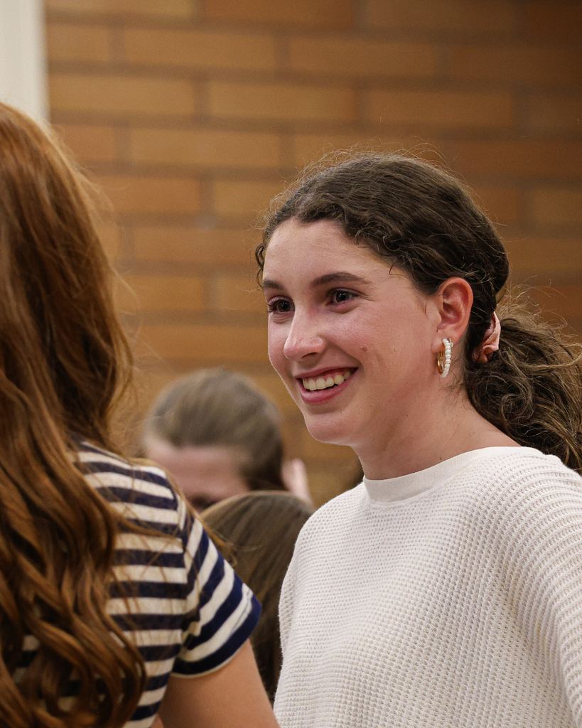A student smiles as they listen intently to a peer.