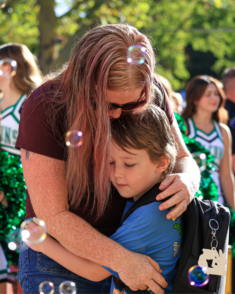 A student hugging a parent as they walk into school.