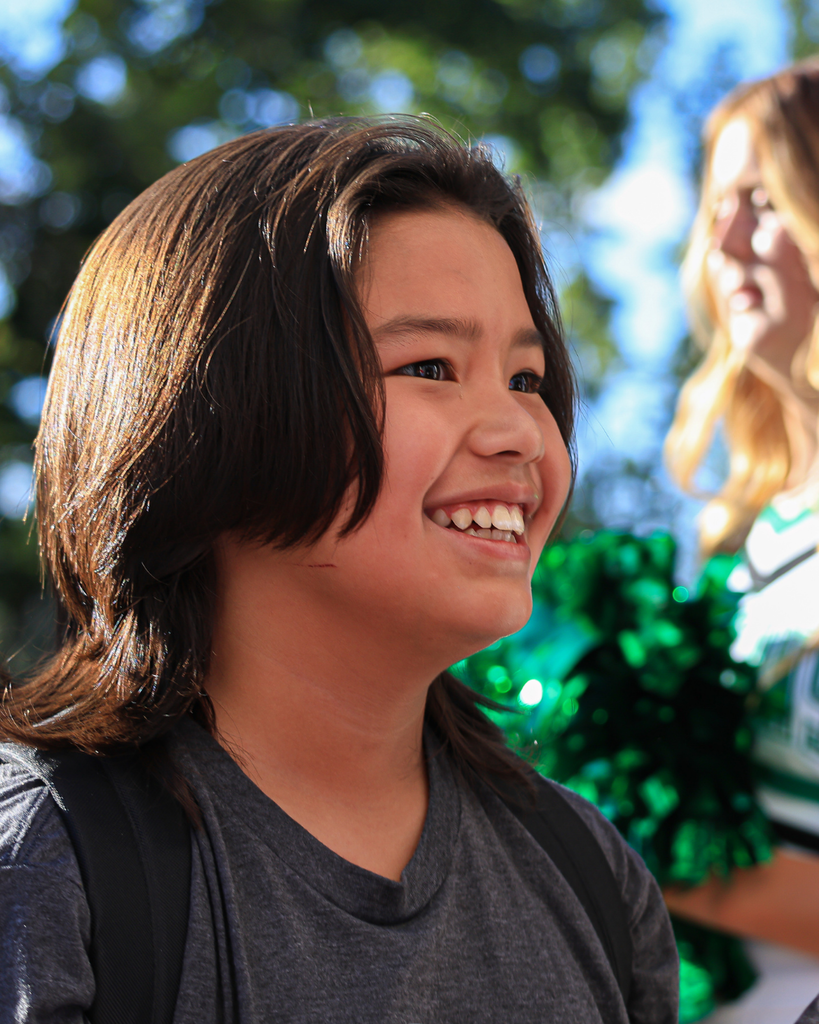A student smiling as they enter the school building.