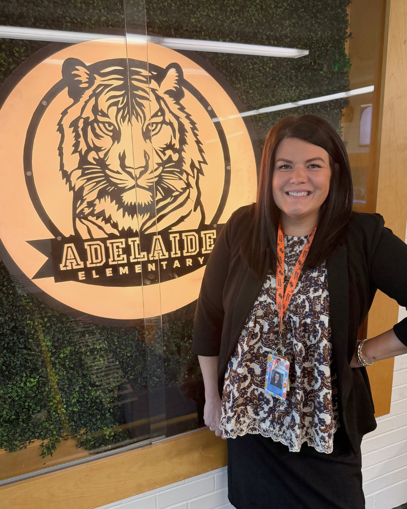 A principal posing next to an Adelaide Elementary sign.