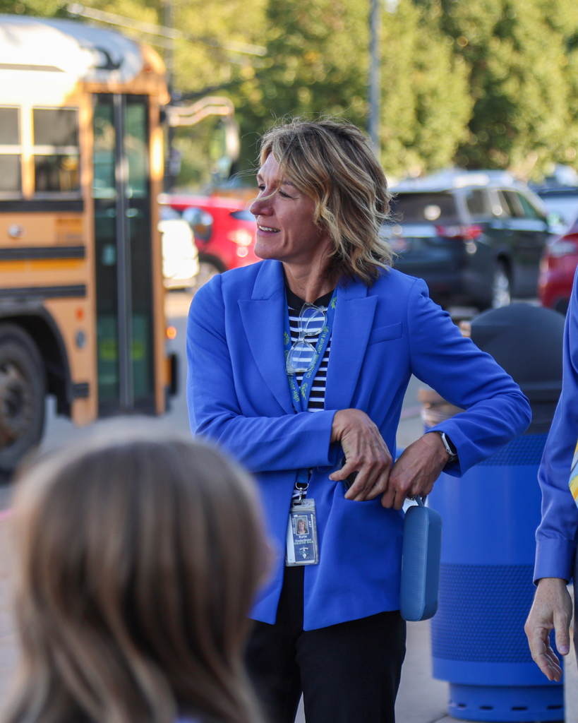 A principal smiling and working near the bus route. 
