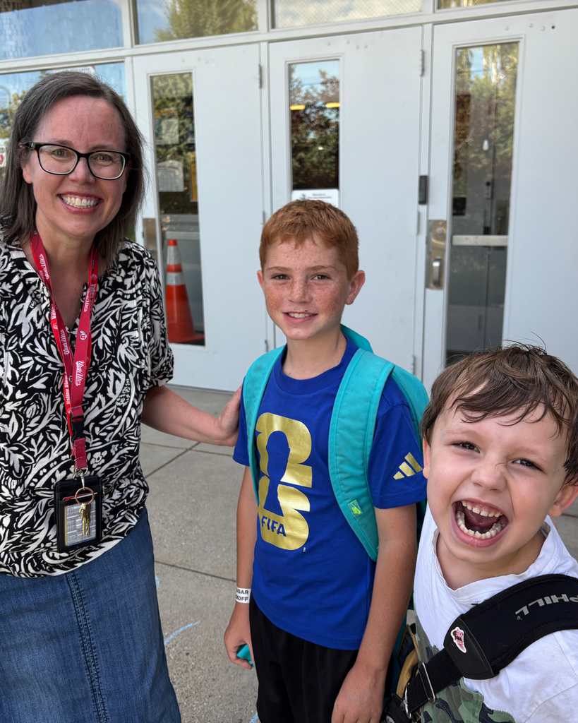 A principal smiling with two students.