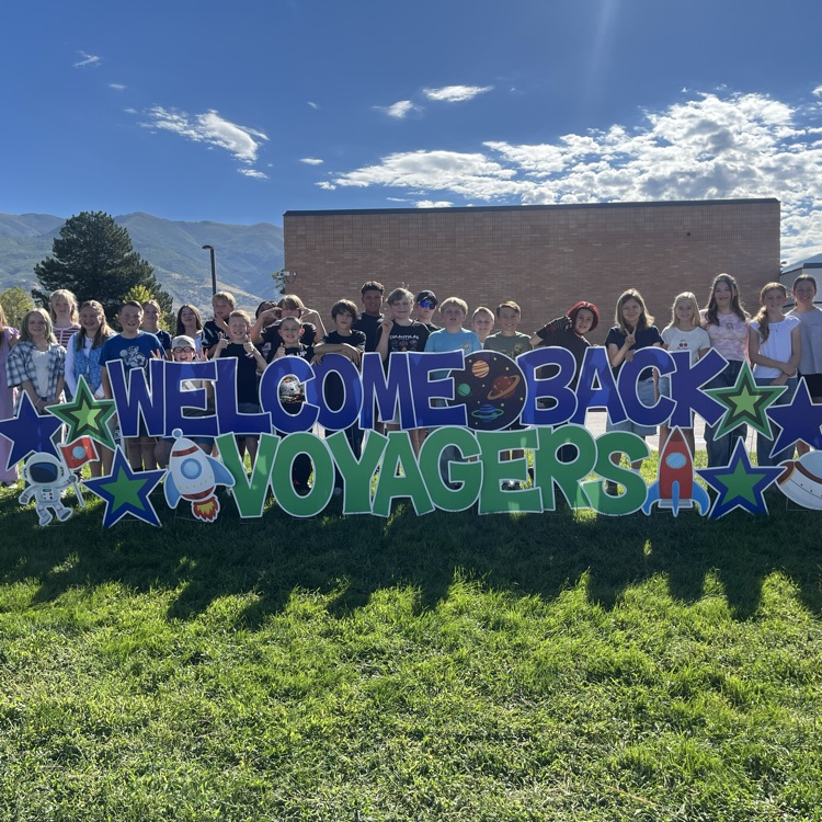 Students standing in front of a welcome back sign  