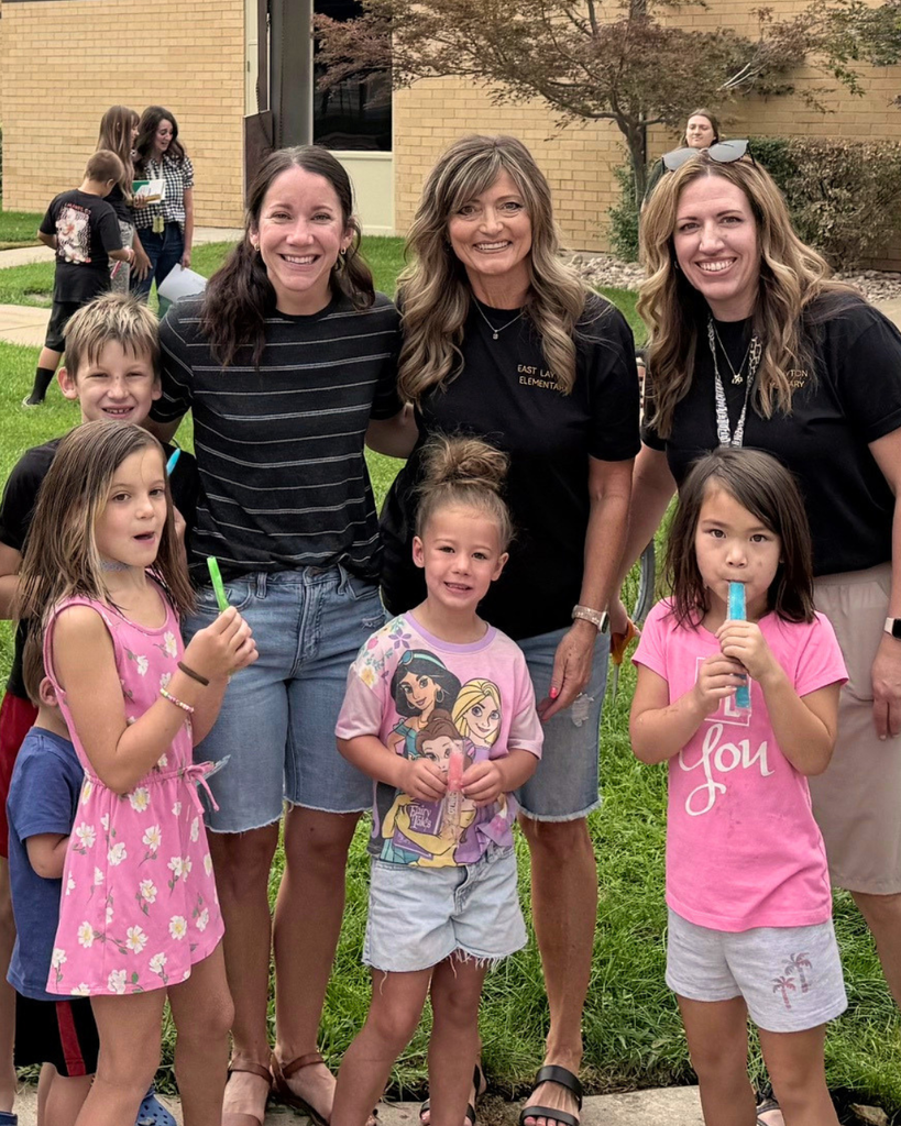 Adults and students smiling while eating popsicles.