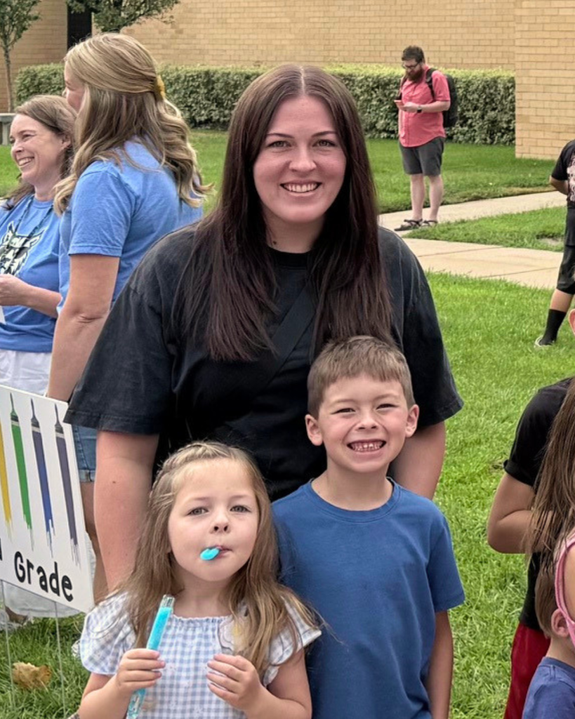Students and an adult smiling. The smallest is eating a blue popsicle.