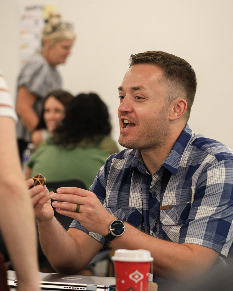 A teacher talks as they hold a dice with many sides.