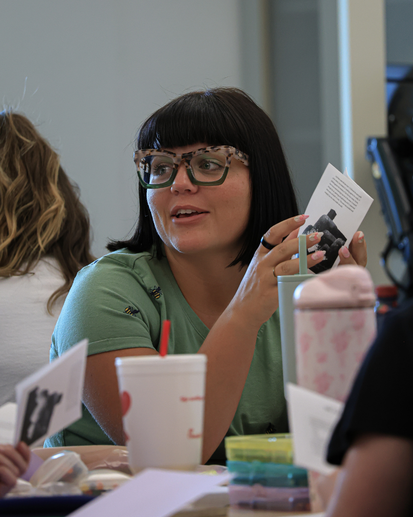 A teacher talks to someone as she holds a paper book.