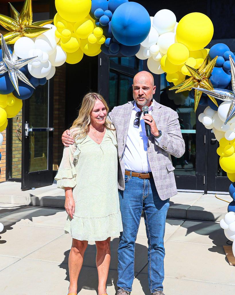 A person side hugs principal Jennifer Malan during ribbon cutting ceremony.