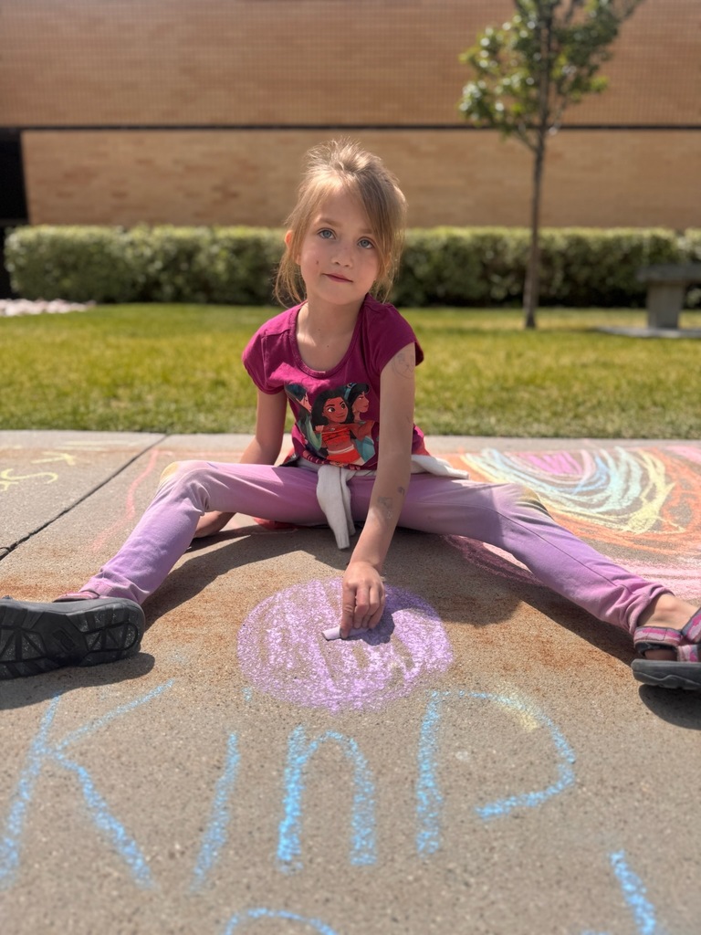 1st grader coloring with sidewalk chalk in front of the school