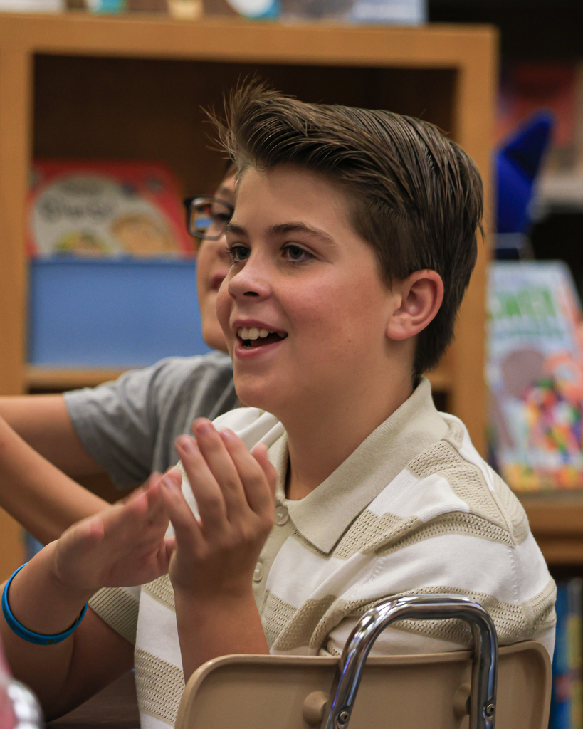 A student smiling while clapping.