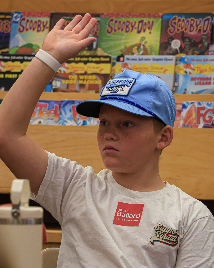 A student in a hat raising their hand.