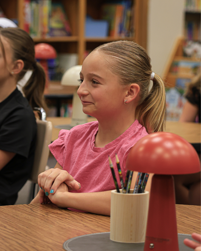 A student smiling with their hands clasped together.