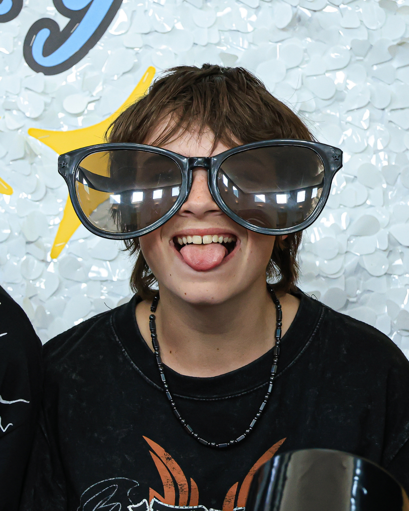 A student wearing gigantic sunglasses sticks their tongue out.