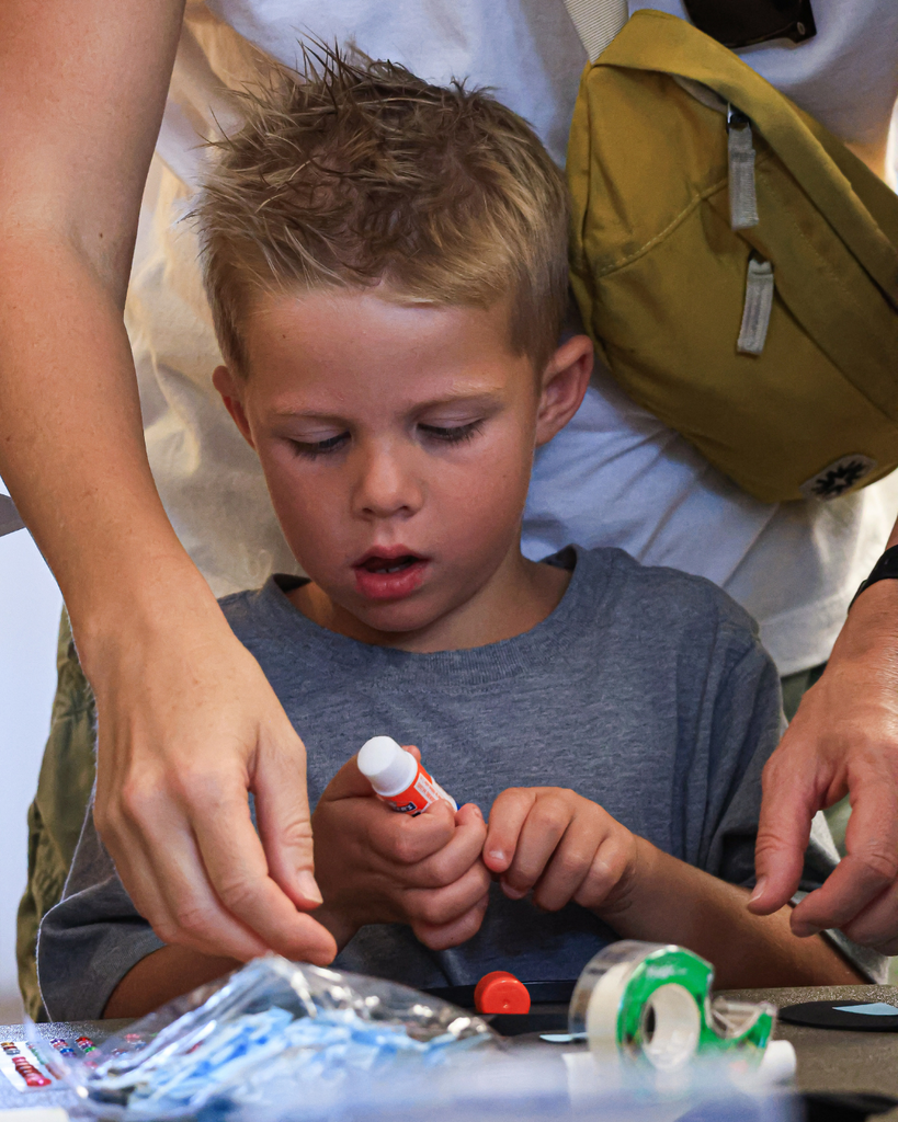 A student unscrewing glue while their parent is looking over them.