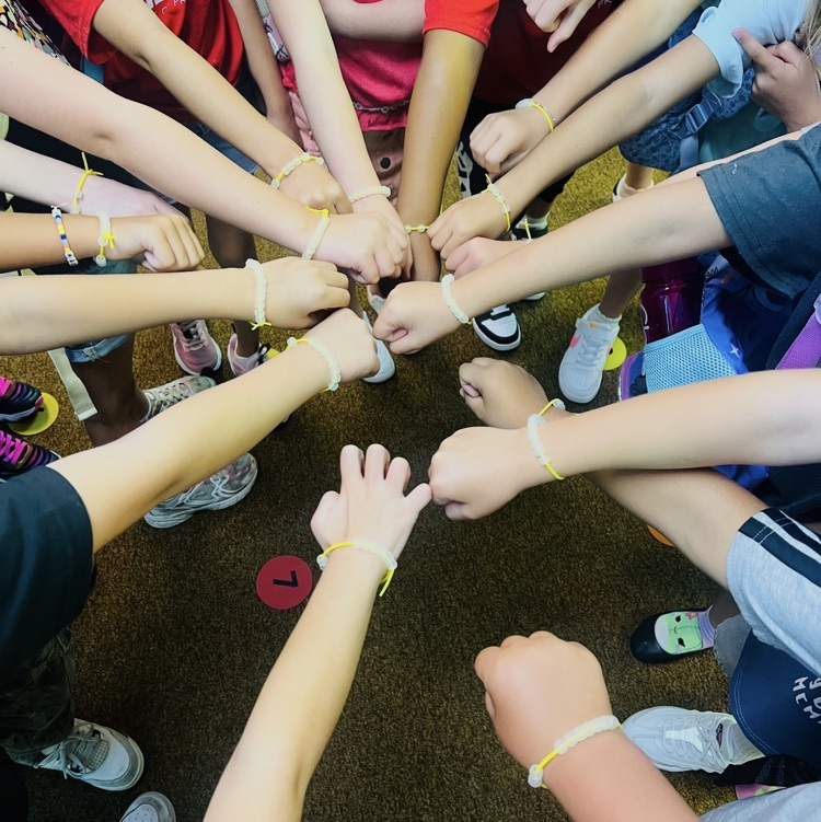 second graders showing off class family bracelets they made