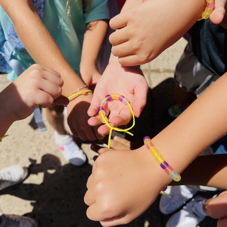 second graders showing off class family bracelets they made