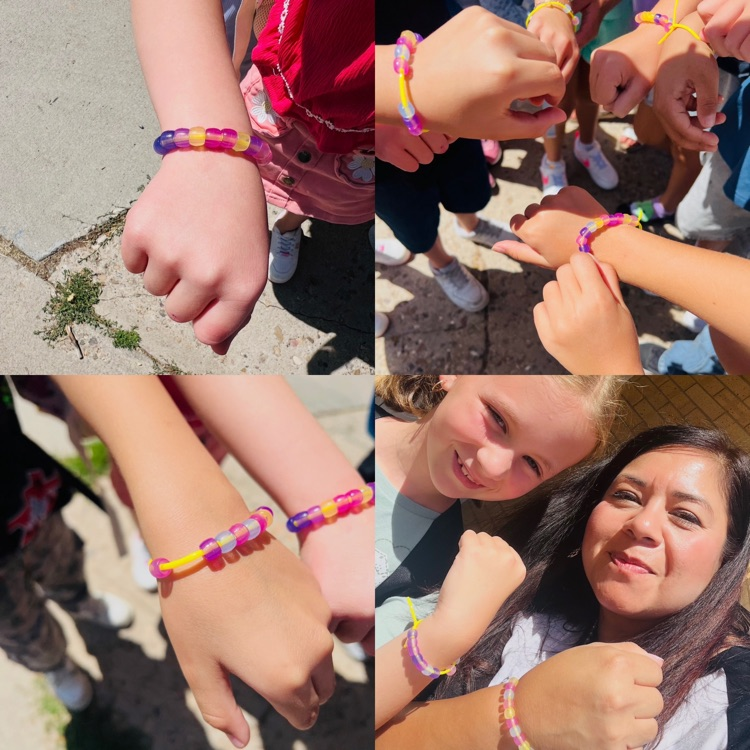 second graders showing off class family bracelets they made
