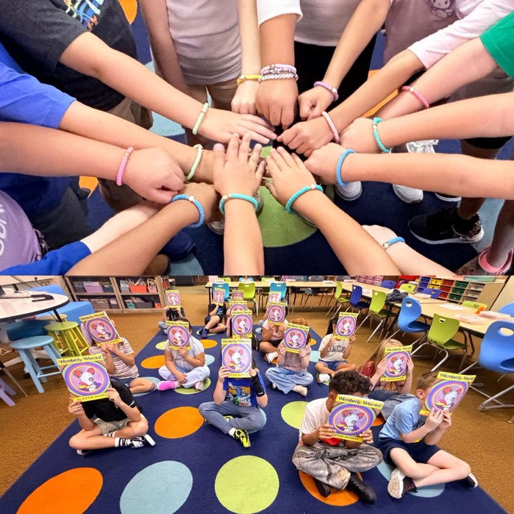 second graders showing class family bracelet and a book 