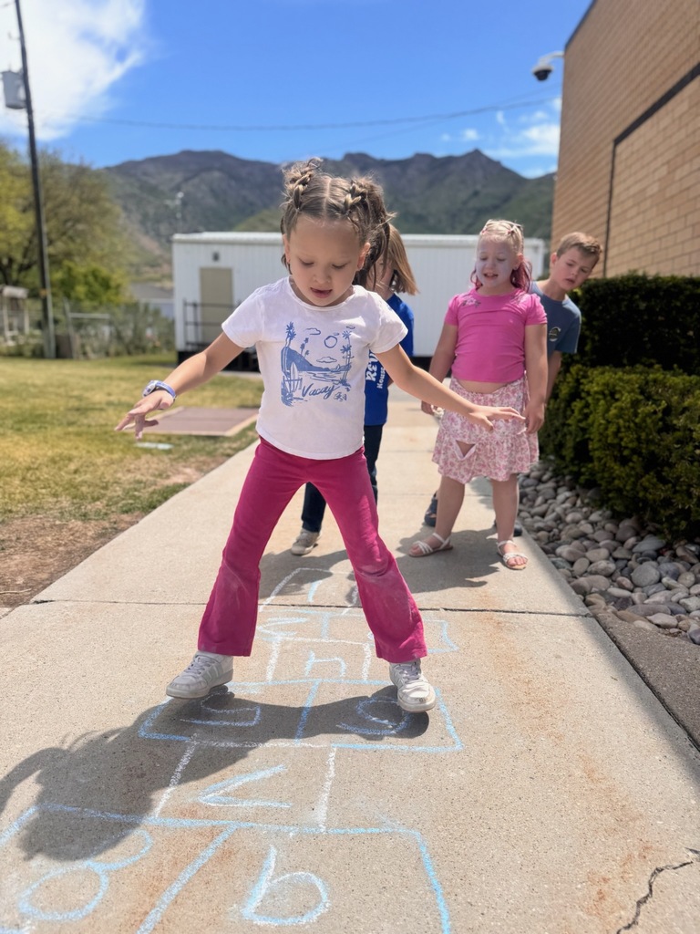 1st graders playing hopscotch on the school sidewalk