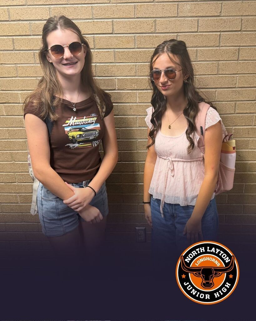 Two students stand in the hall wearing sunglasses