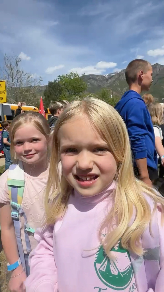 Two 2nd grade girls in pink standing in front of their school