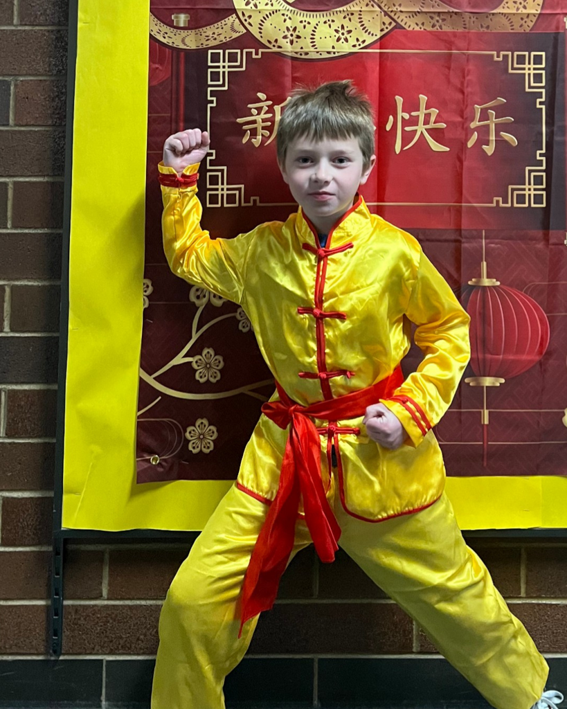 A student in a yellow and red outfit holds his fists. 