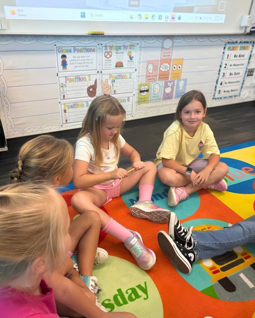 Students sit together on the classroom rug during a group learning activity.