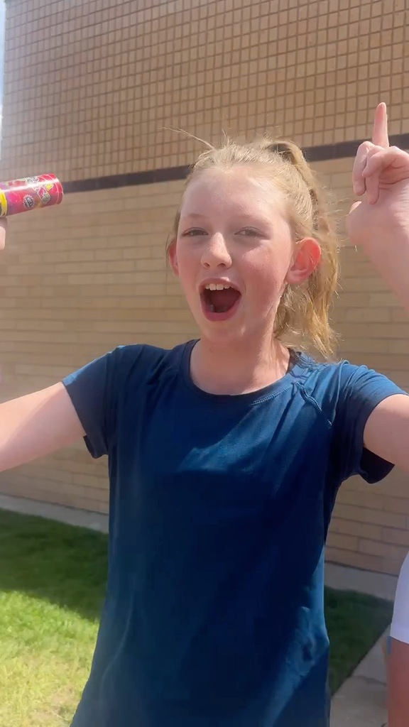 6th Grade Student cheering in front of school