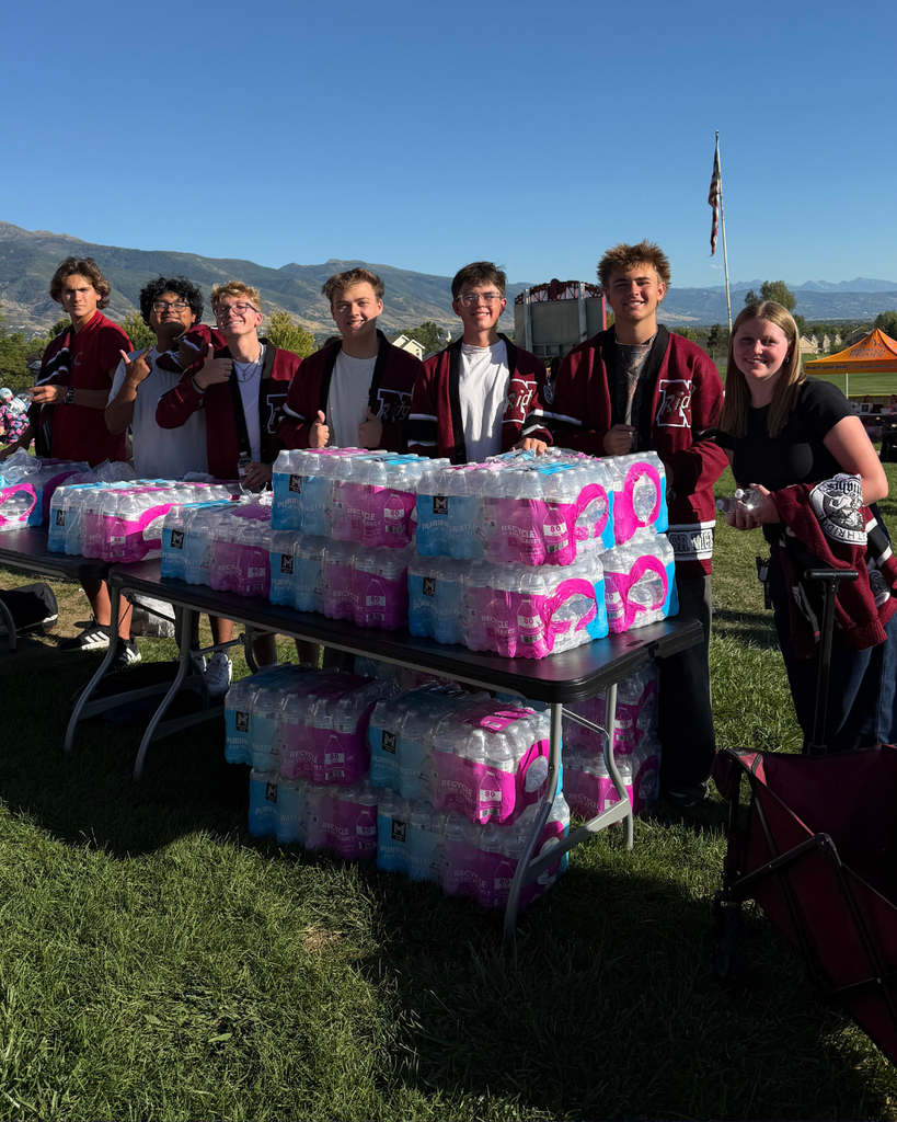Students standing in front of a bunch of water bottles.