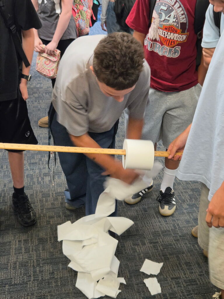 Student quickly unrolling toilet paper for an activity. 