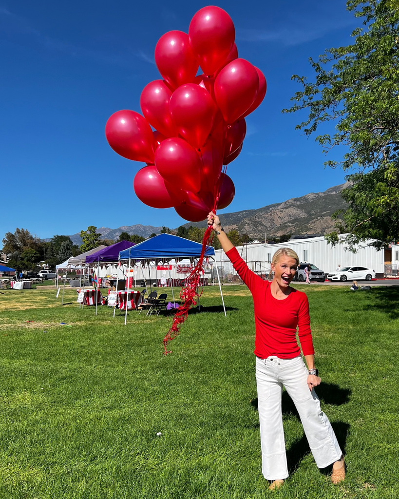 a parent volunteer holds a bunch of red balloons