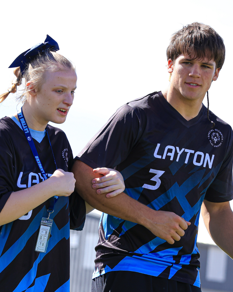 Two students link arms during a soccer game.