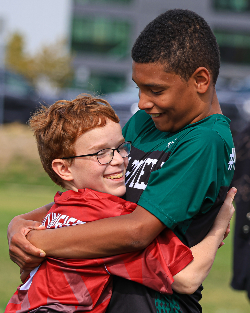 Two students hug during a soccer game.
