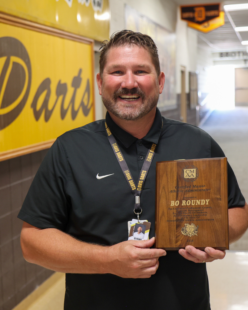 Roundy smiling while holding a plaque that says: "Certified Master Athletic Administrator"