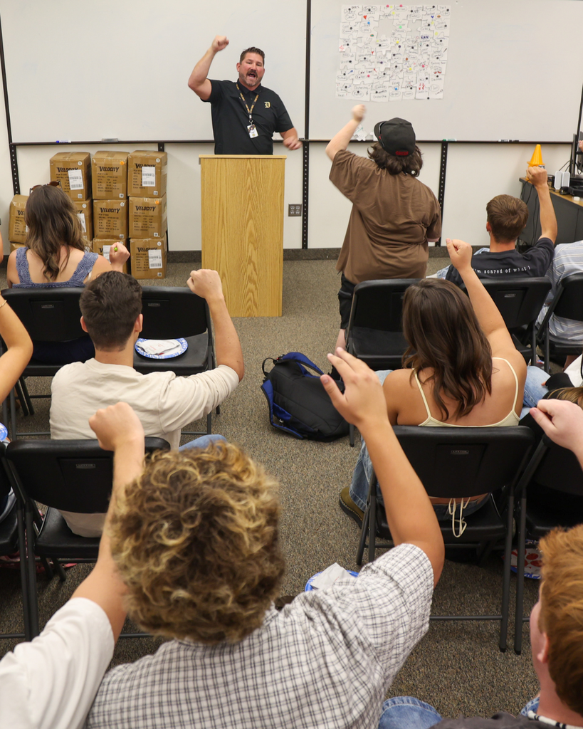 Roundy engaging with his class. Many students arms are raised.
