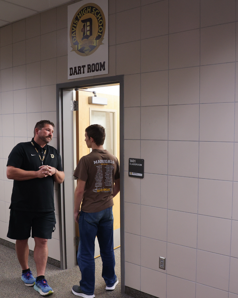 A teacher conversing with a student in the hallway.