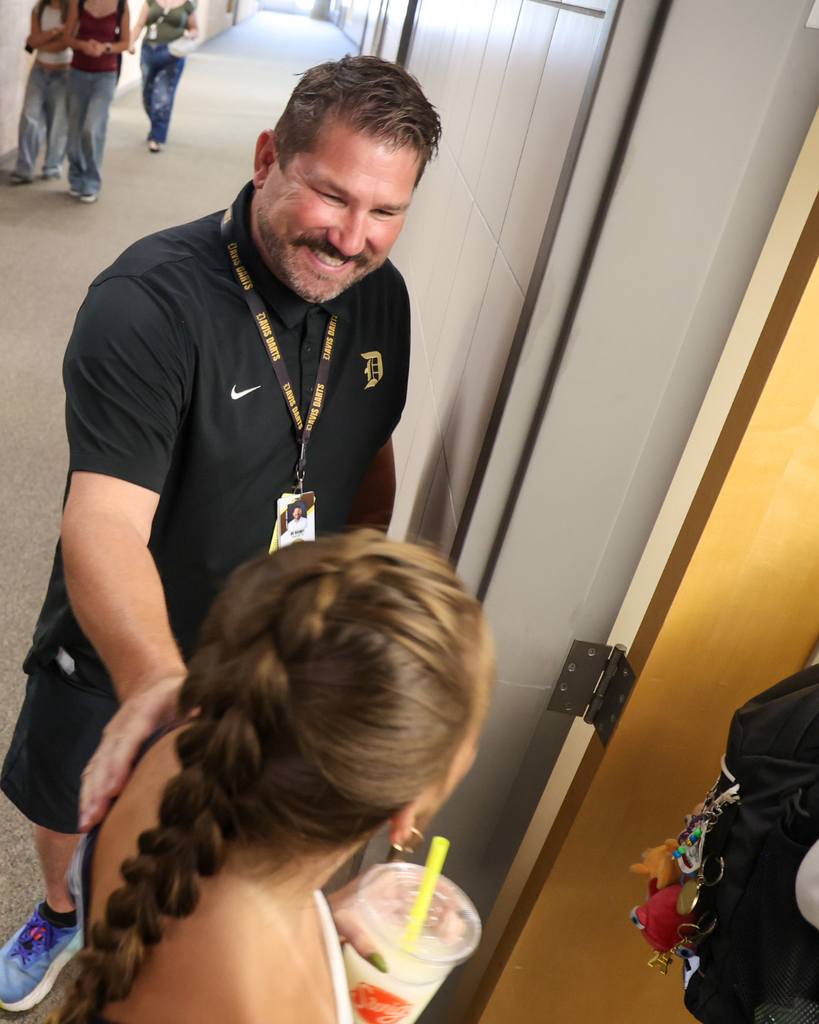 A teacher welcomes a student into class. 