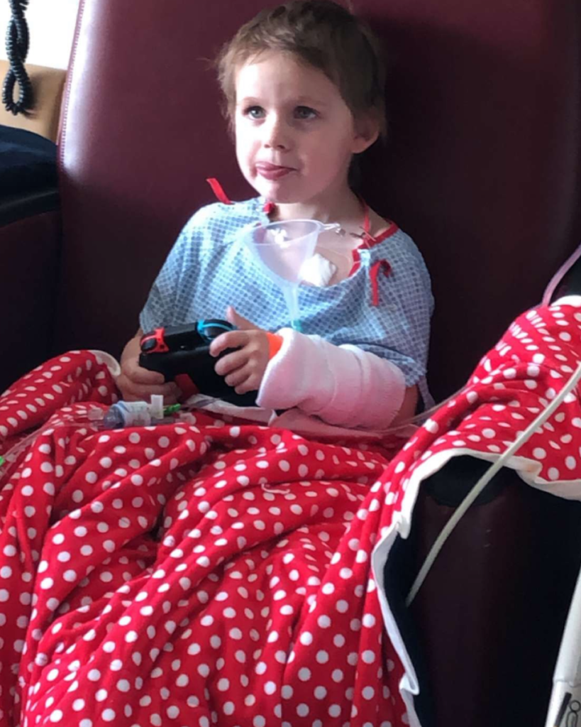 A student playing a video game with a blanket on.