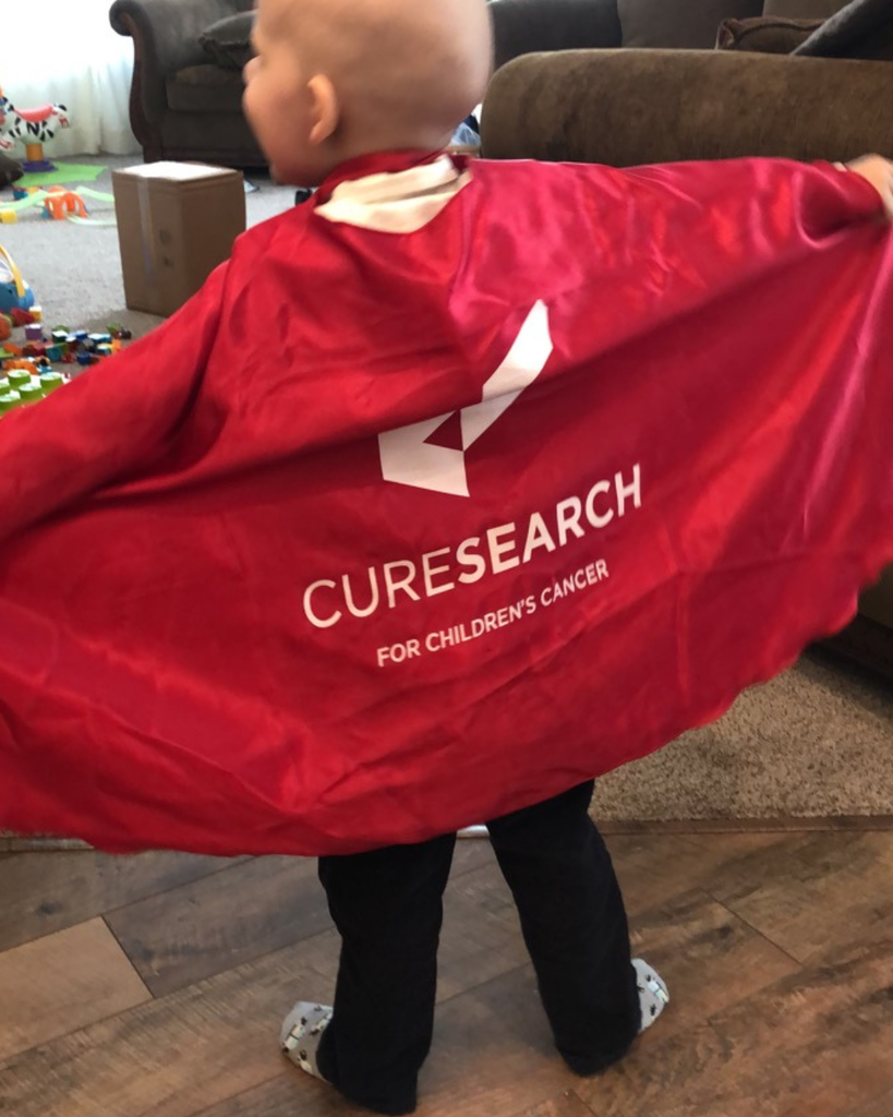 A student showing the back of their cape that reads: "Curesearch for Children's Cancer"