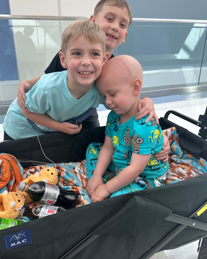 Two students hugging another student smiling.