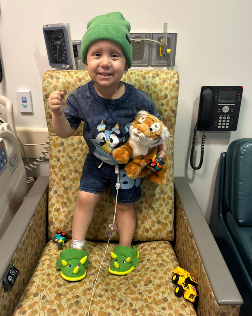 A student in a beanie standing on a chair and smiling.