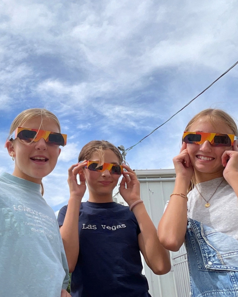 three students pose with their solar eclipse glasses
