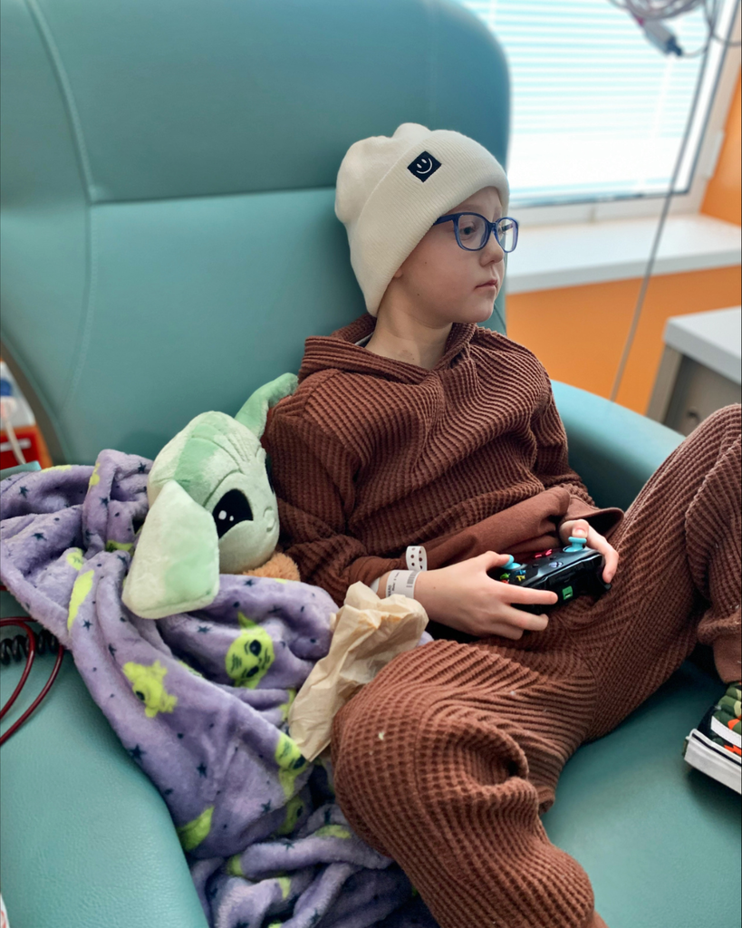 A student playing a video game with a blanket on.