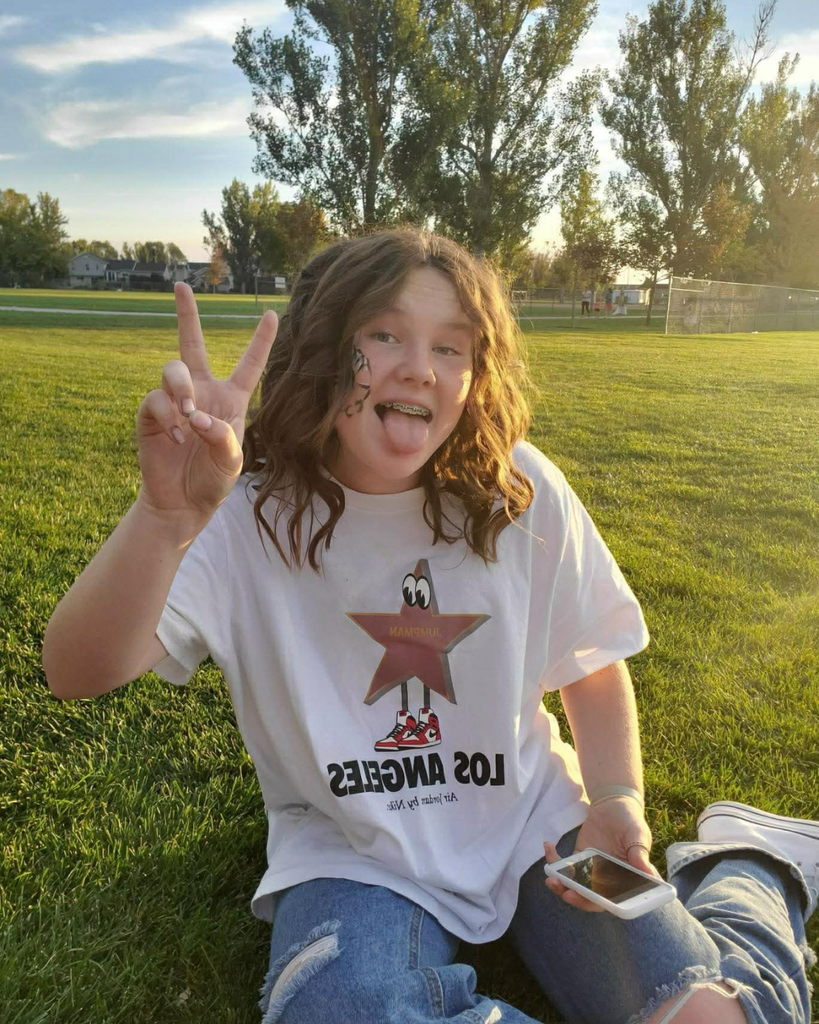 A student outside giving a "peace" sign and sticking their tongue out. 